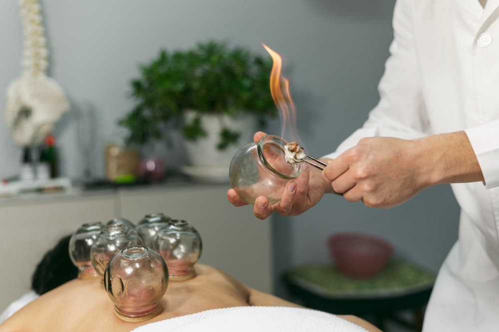 Ayurvedic surgeon performing a Kshar Sutra para-surgical procedure in a sterile setup.
