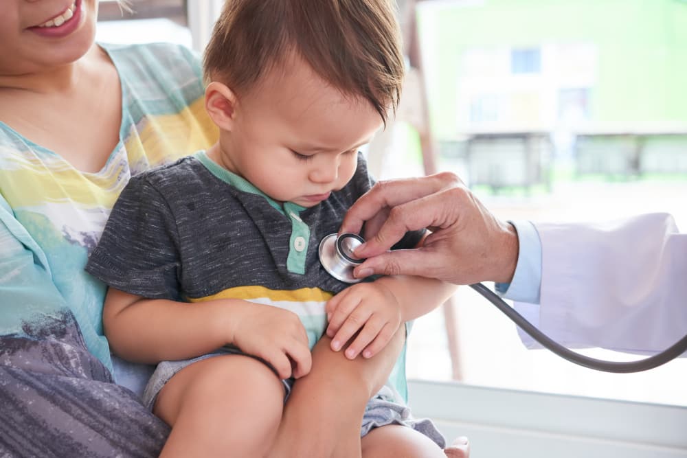 Ayurvedic paediatrician examining a child during a Kaumarbhritya consultation.