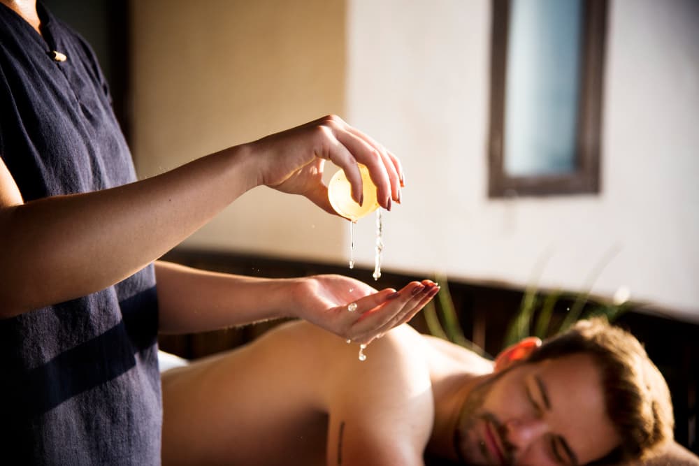 Therapist performing classical Panchakarma Abhyangam with medicated oil in a calm therapy suite.
